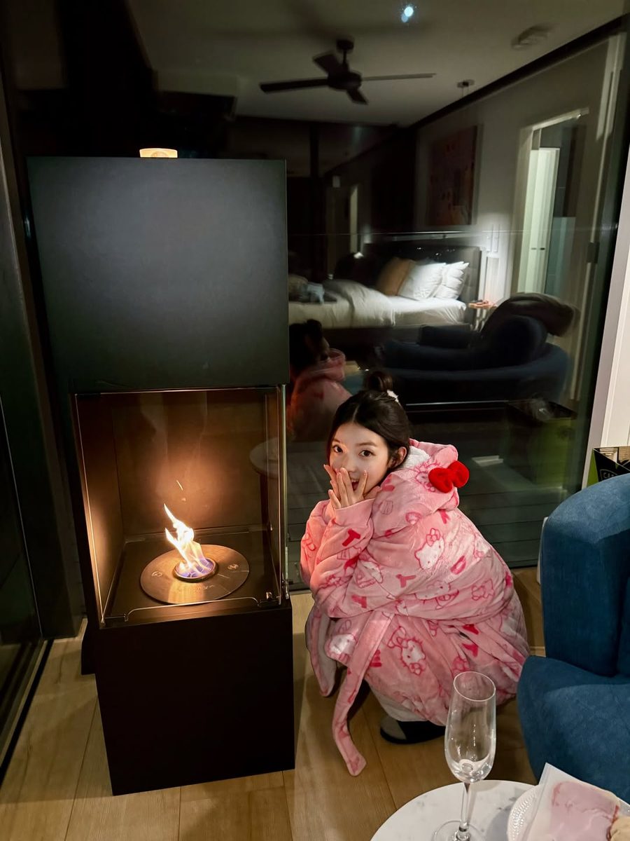Customer in a pink hooded robe by the fireplace